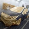 Vue avant d'une voiture peinte dans un atelier de carrosserie avec papier de masquage